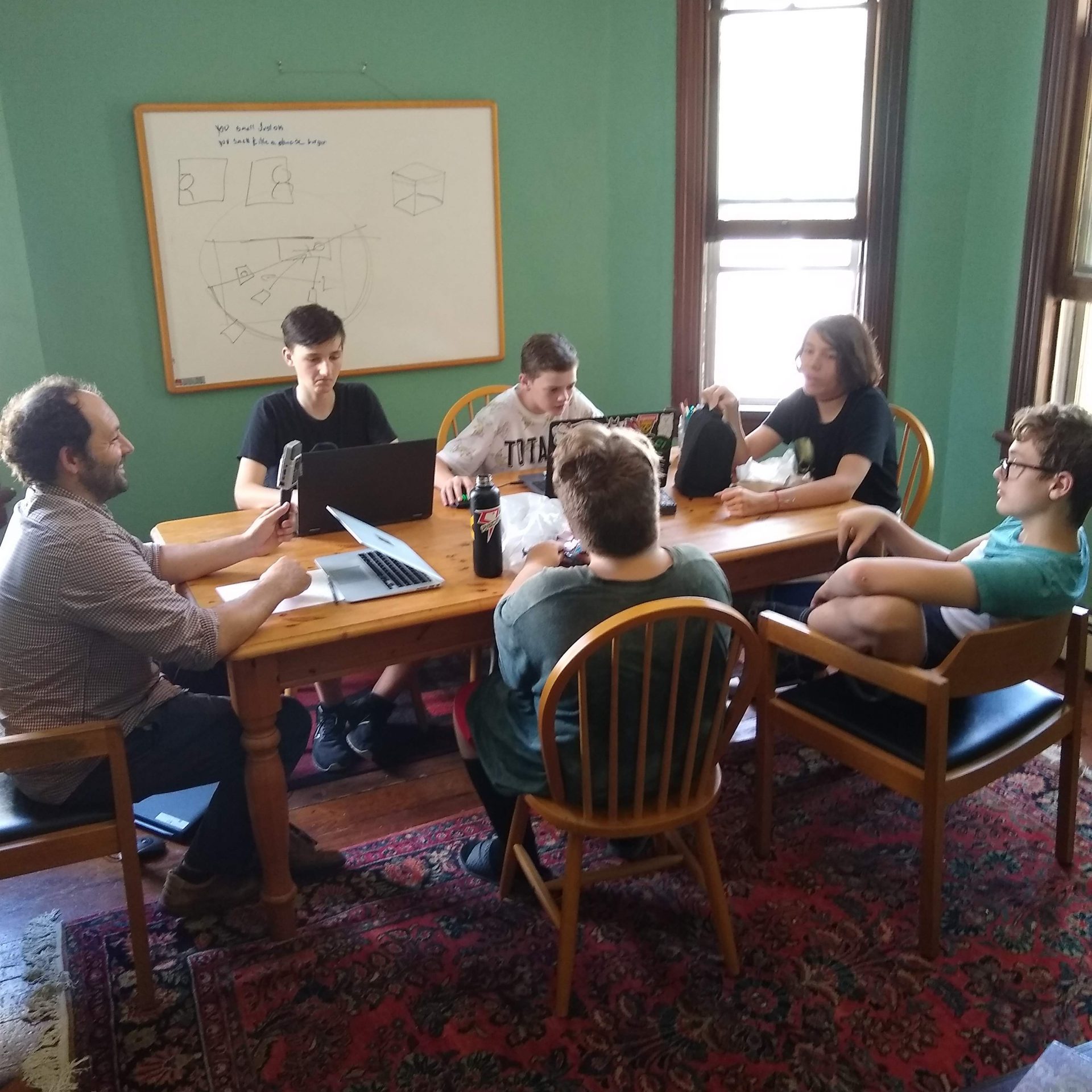 Scott and five teens around a table in Writing Workshop class