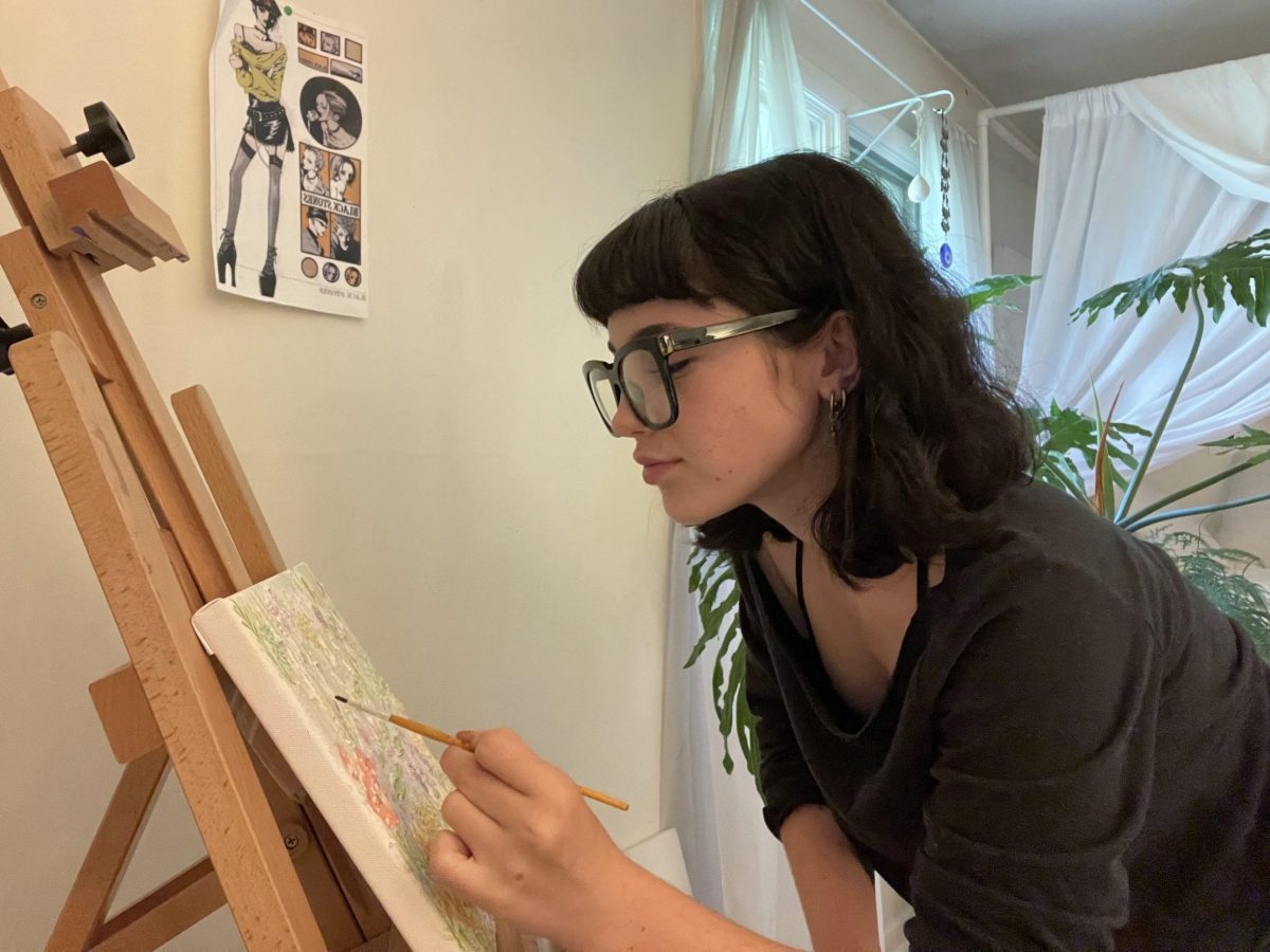 a teen painting a canvas on an easel