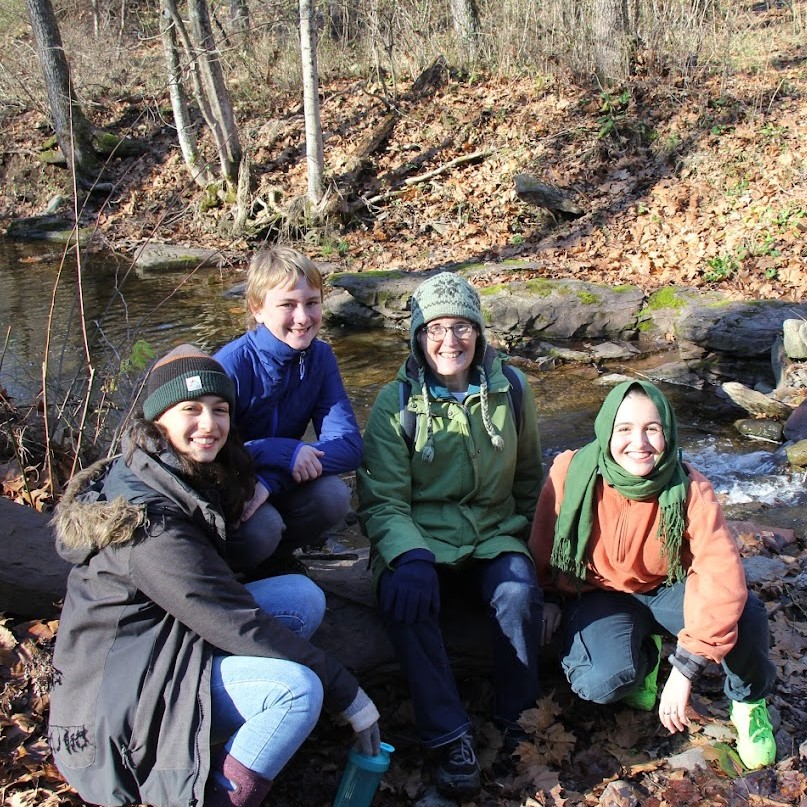 Alison and three teens sitting by a stream in winter near Frenchtown, NJ