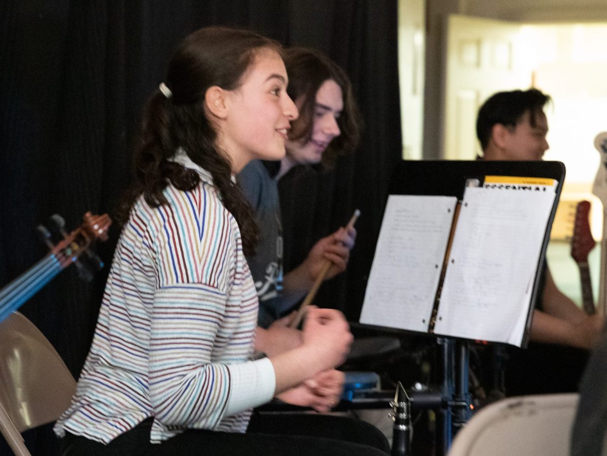 Teen leaning forward toward music stand with two other musicians in the background